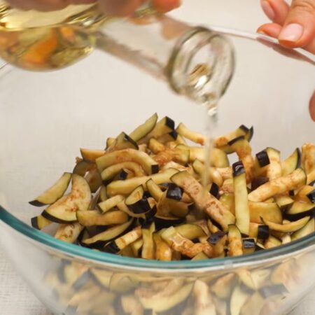 В подготовленные баклажаны добавляем 1-2 ст. л. растительного масла и перемешиваем.