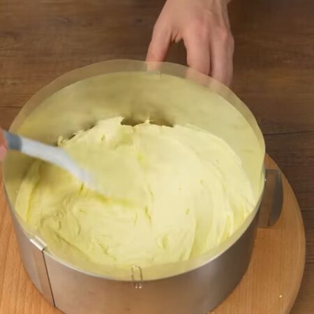 Сверху кладем половину приготовленного крема. Равномерно распределяем его по поверхности бисквита.