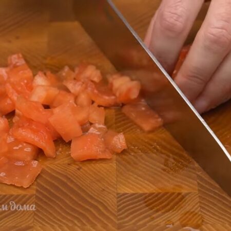 Помидор, который остался без шкурки, разрезаем на 4 части. У помидора вырезаем серединку с семенами для того, чтобы не стекала лишняя жидкость. Мякоть помидора нарезаем кубиками.