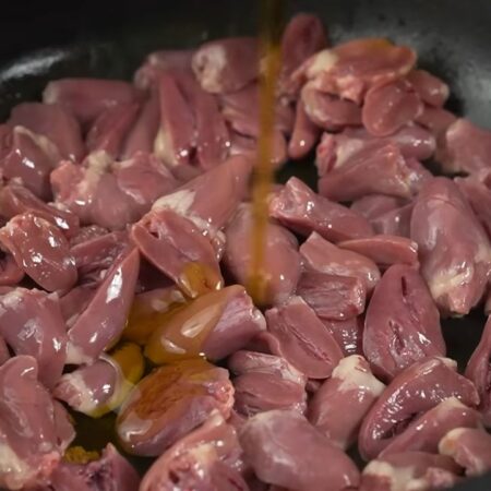 В эту же сковороду кладем уже подготовленные куриные сердечки. Добавляем еще немного растительного масла. Обжариваем их на большом огне примерно 3-4 минуты. Периодически перемешиваем.