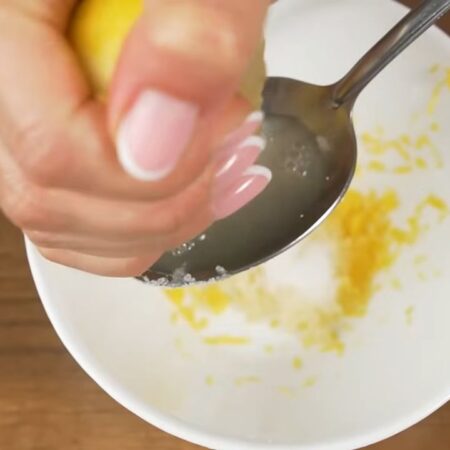 Готовим маринад для рыбы.
С половины лимона, с помощью мелкой терки, снимаем цедру.
Сюда же, в мисочку, выдавливаем через пресс 1 зубчик чеснока. Добавляем соль. И выжимаем 2 столовых ложки лимонного сока. 