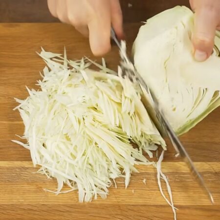 Сначала приготовим начинку для пирога.
Белокочанную капусту шинкуем ножом. Понадобится примерно 150-180 г капусты. Уже нашинкованную капусту еще несколько раз перерезаем ножом чтобы она получилась более мелкая. Подготовленную капусту перекладываем в миску.