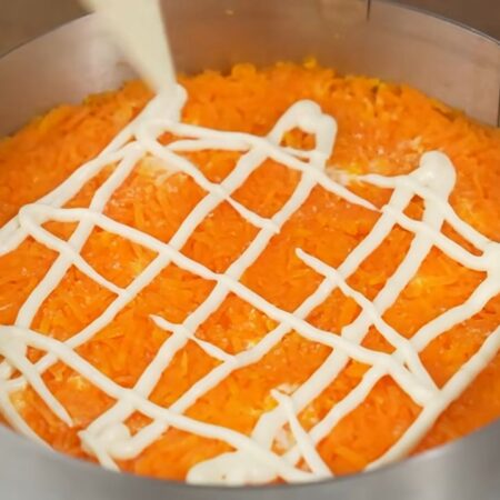 Сверху выкладываем оставшуюся морковку. Распределяем и утрамбовываем. Морковку немного солим и делаем сеточку из майонеза.