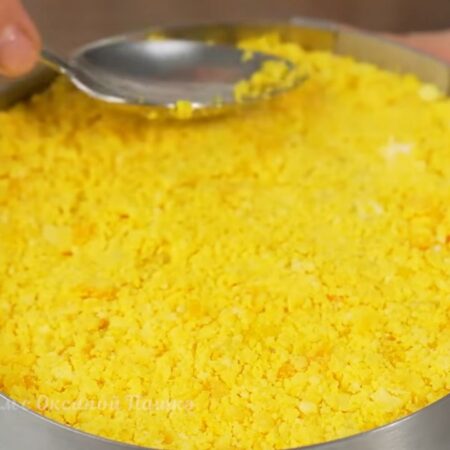 На кукурузу высыпаем вареный желток. Равномерно его распределяем и утрамбовываем ложкой.
Салат готов, даем ему настояться в холодильнике.
