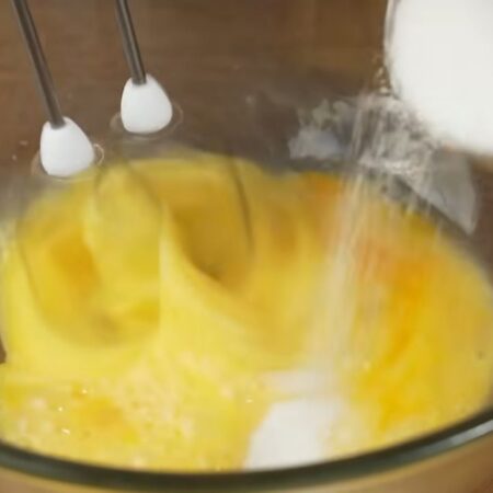 В отдельную миску разбиваем 5 яиц. Начинаем их взбивать и постепенно насыпаем 50 г сахара.
