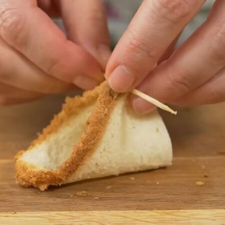 Каждый треугольник сворачиваем и скрепляем два конца хлеба зубочисткой. Скреплять нужно в более плотных местах, там где находится хлебная корочка.