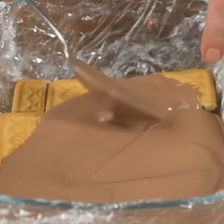 На печенье наливаем 2-3 столовых ложки приготовленного крема. Равномерно его распределяем. На крем снова выкладываем слой из печенья. Опять наносим крем. Таким методом собираем весь торт.