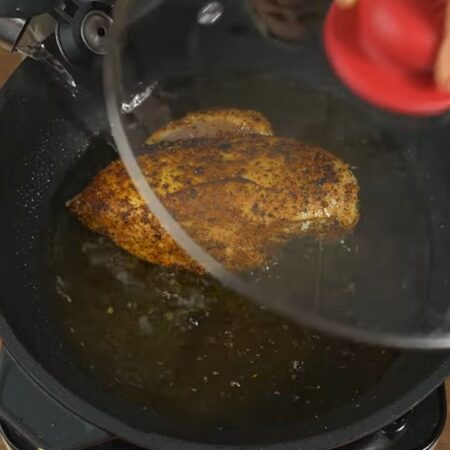 Филе поджарилось с двух сторон, наливаем в сковороду примерно полстакана воды. Накрываем крышкой и тушим мясо примерно 15-20 минут на маленьком огне.