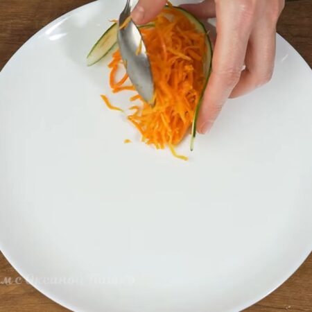 Складываем салат-закуску.
На большое плоское блюдо выставляем пластику огурца. Кладем подготовленную морковь по-корейски. В каждую пластинку огурца кладем примерно 2-3 столовых ложки моркови. Заворачиваем огурец. Получился вот такой лепесток.