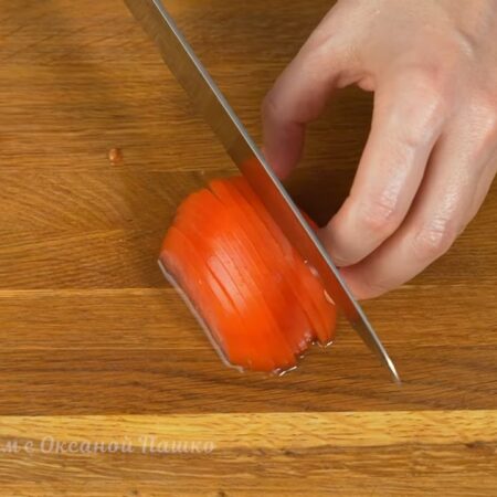 Один помидор разрезаем пополам. Одну из половинок помидора нарезаем тонкими пластинками.