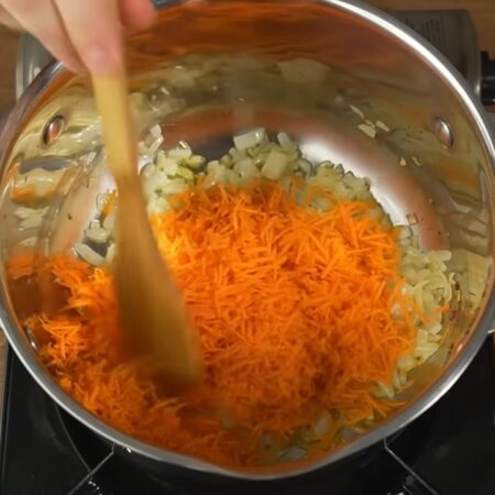 Лук немного подзолотился, кладем тертую морковь. Перемешиваем и готовим еще примерно 1-2 минуты.

