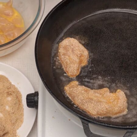 Каждый кусочек куриного филе обваливаем в панировочной смеси и выкладываем на раскаленную сковороду с подсолнечным маслом.