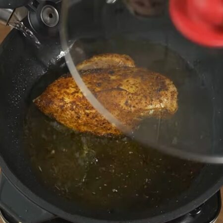 Филе поджарилось с двух сторон, наливаем в сковороду примерно полстакана воды. Накрываем крышкой и тушим мясо примерно 15-20 минут на маленьком огне.
