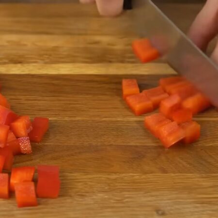У перца срезаем верхнюю и нижнюю части, вырезаем семенную коробочку. Перец нарезаем пластинками, а затем кубиками.