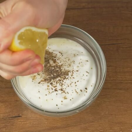 Готовим соус. Берем 4 столовых ложки густого несладкого йогурта (это примерно 150 г). Йогурт солим по вкусу и перчим черным молотым перцем. Сюда же выдавливаем примерно 1 столовую ложку лимонного сока.