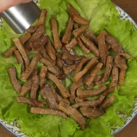 Первым слоем кладем мясо и равномерно его распределяем по блюду. Мясо солим и перчим черным молотым перцем. Я это делаю сейчас, так как при приготовлении мяса забыла его посолить.
